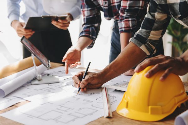 Engineer teams meeting working together wear worker helmets hardhat on construction site in modern city.Asian industry professional team